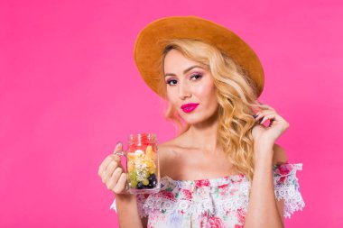 Meyve kavanoz pembe bir arka plan üzerinde olan güzel kadın