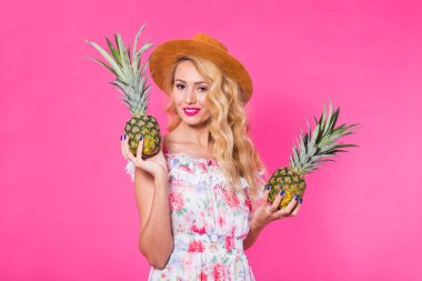 Bir ananas pembe bir arka plan üzerinde tutan mutlu genç kadın. Yaz, diyet ve tatil kavramı