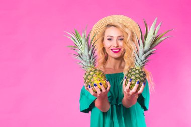 Bir ananas boşaltmak ile pembe bir arka plan üzerinde tutan mutlu genç kadın. Yaz, diyet ve tatil kavramı