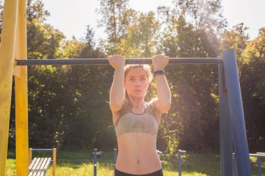 Barfiks çekmek açık spor zeminde yapıyor genç güzel kız