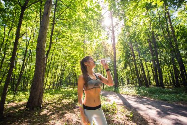 Fitness içme suyu ve sıcak yaz günü parkta egzersiz sonra terleme güzel kadın. Çalışma sonra kadın atlet.