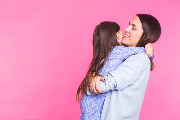 Personnes, bonheur, amour, concept de famille et de maternité - heureuse petite fille étreignant et embrassant sa mère sur fond rose avec copyspace — Photo