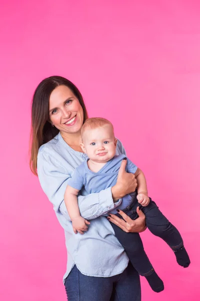 Mutlu genç anne bebek çocuk üzerinde pembe bir arka plan ile — Stok fotoğraf