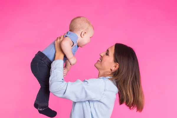 Feliz joven madre con un bebé niño sobre fondo rosa — Foto de Stock