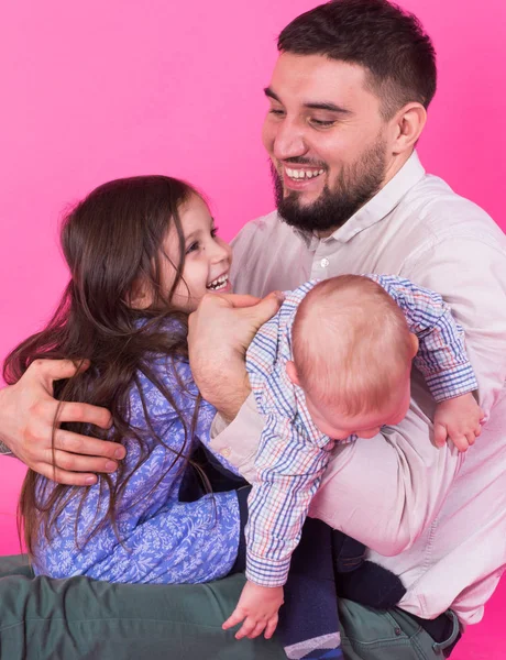 Schöner Vater mit seiner kleinen Tochter und seinem kleinen Sohn auf rosa Hintergrund — Stockfoto