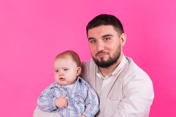 Baby in Papas Händen. rosa Hintergrund. — Stockfoto