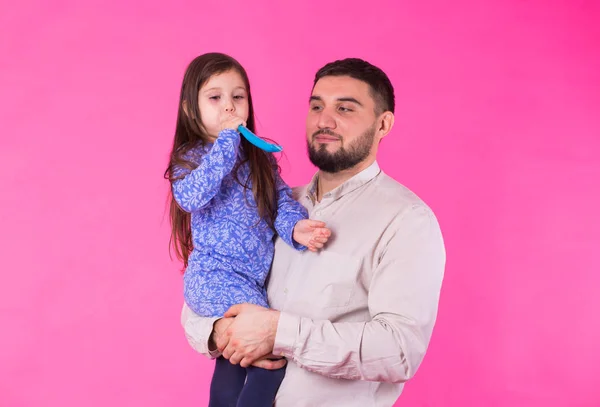 Glücklicher Vater mit seiner kleinen Tochter auf rosa Hintergrund — Stockfoto
