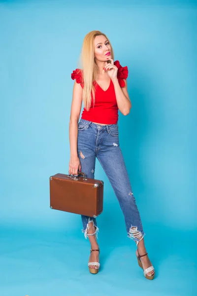 Estate, viaggi, persone e vacanze concetto - alla moda giovane donna bionda con valigia retrò isolato su sfondo blu — Foto Stock