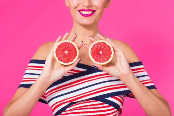 Zamknij się młodej kobiety na różowym tle posiada wycięcie pomarańczowy w jej ręce i śmieje się. Kolor koncepcja obsesja. — Zdjęcie stockowe