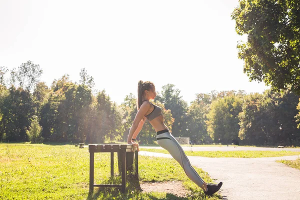 Fitness, deporte, ejercicio, entrenamiento y concepto de personas - pareja haciendo ejercicio de inmersión de tríceps en el banco de la calle de la ciudad . — Foto de Stock