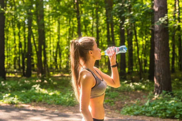 Femme sportive boire de l'eau en plein air le jour ensoleillé. — Photo