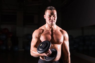 Yakışıklı güç dumbbell atletik adamla. Altı paket, mükemmel abs, omuzlar, pazı, triceps ve göğüs ile güçlü vücut geliştirmeci