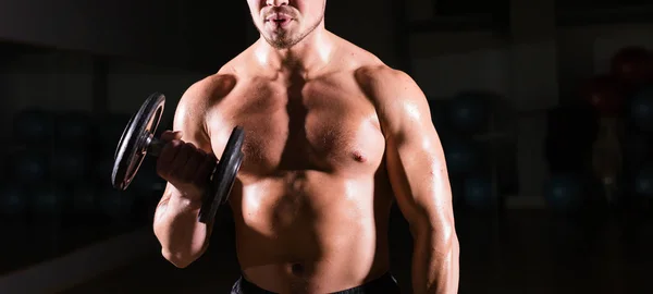 Hombre deportivo haciendo ejercicio con pesas. Tipo musculoso sobre fondo negro. Fuerza y motivación . — Foto de Stock