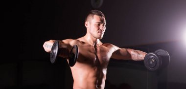 kas genç adam koyu arka plan üzerinde ağırlık kaldırma