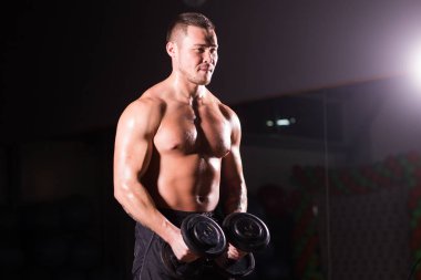 Yakışıklı güç dumbbell atletik adamla. Altı paket, mükemmel abs, omuzlar, pazı, triceps ve göğüs ile güçlü vücut geliştirmeci