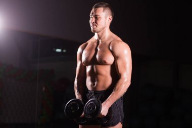 kas genç adam koyu arka plan üzerinde ağırlık kaldırma