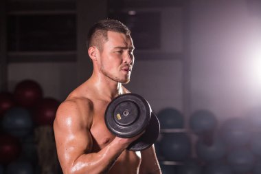 Yakışıklı güç dumbbell atletik adamla. Altı paket, mükemmel abs, omuzlar, pazı, triceps ve göğüs ile güçlü vücut geliştirmeci