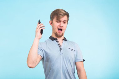 Portre kızgın genç adam, adam deli öğrenci telefon üzerinde mavi arka plan üzerinde bağırarak kapatın. Negatif insan duygu yüz ifade duygu tutum