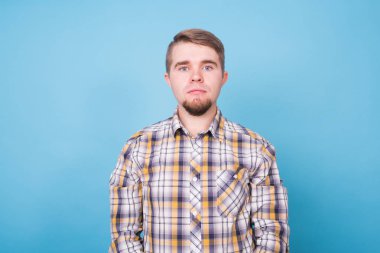 Yakışıklı bir genç adam boşaltmak ile mavi arka plan karşı portresi