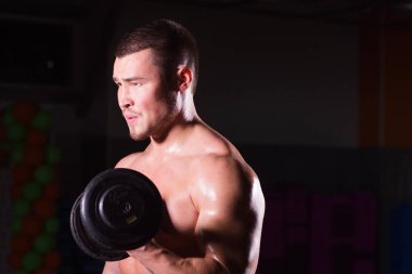 Spor salonunda spor yapan kaslı bir adam, pazularıyla egzersiz yapıyor. Güçlü erkek, çıplak karın kasları var..