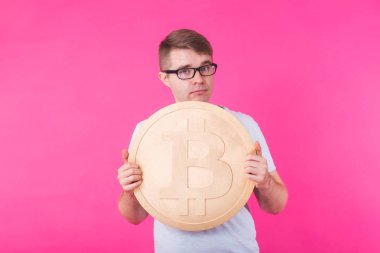 Büyük altın bitcoin, pembe arka plan tutan adam. Kripto para birimi, sanal para, internet ve ekonomi kavramı
