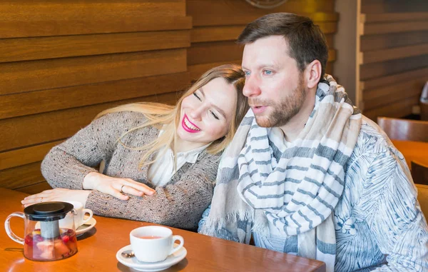 Feliz jovem casal está bebendo café e sorrindo enquanto sentado no café . — Fotografia de Stock