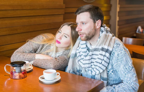 Feliz joven pareja está bebiendo café y sonriendo mientras se sienta en el café . — Foto de Stock