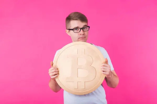 Hombre sosteniendo bitcoin grande de oro sobre fondo rosa. Cripto moneda, dinero virtual, internet y concepto de economía — Foto de Stock