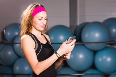 Smartphone ve fitness salonunda egzersiz molası izci ile genç kadın