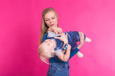 mutlu küçük kız ve annesi pembe arka plan üzerinde eğleniyor