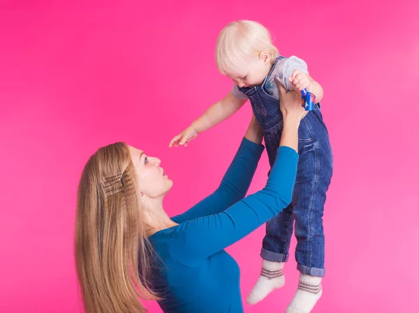 Familia divertida sobre fondo rosa. Madre y su hija. Mamá y el niño se están divirtiendo . — Foto de Stock