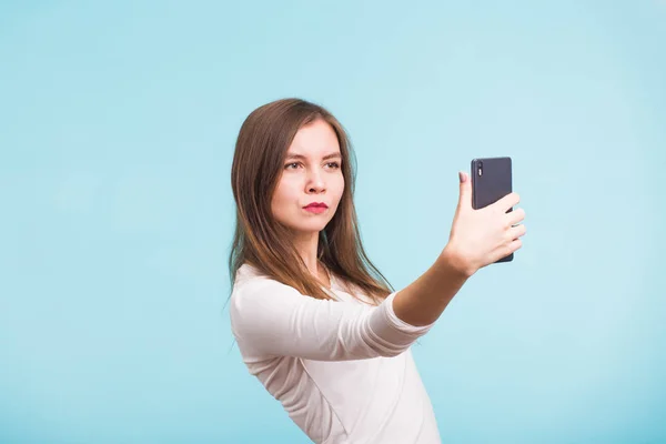 Menina bonita tomando selfie sobre fundo azul — Fotografia de Stock