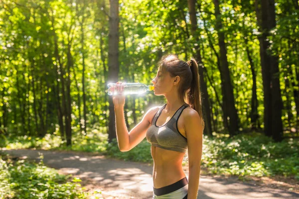 Femme sportive boire de l'eau en plein air le jour ensoleillé. — Photo