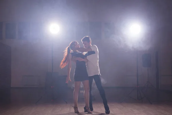 Geschickte Tänzer, die im dunklen Raum unter dem Licht und Rauch des Konzerts auftreten. sinnliches Paar, das einen künstlerischen und emotionalen zeitgenössischen Tanz aufführt — Stockfoto