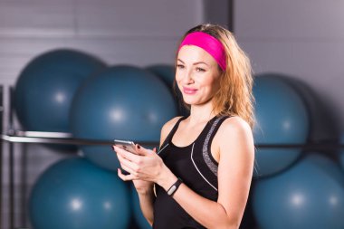Smartphone ve fitness salonunda egzersiz molası izci ile genç kadın