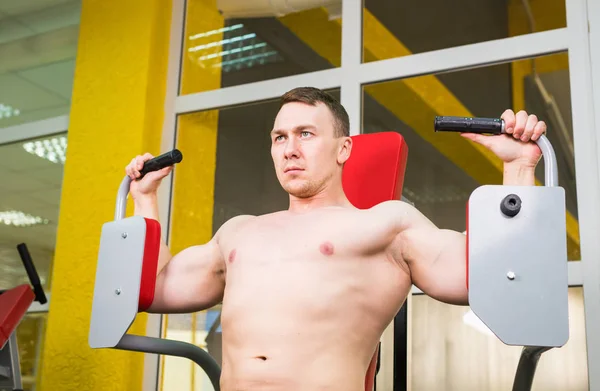 Svalnatý muž dělá motýl cvičení ve fitness centru. — Stock fotografie