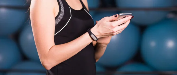 Nő használ sejt telefon és fitness tracker edzőteremben közelről — Stock Fotó