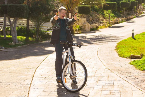 Όμορφος νεαρός άνδρας με ποδήλατο δείχνει τους αντίχειρες στο πάρκο ηλιόλουστη ημέρα — Φωτογραφία Αρχείου