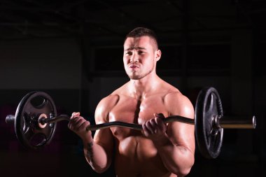 kas genç adam koyu arka plan üzerinde ağırlık kaldırma