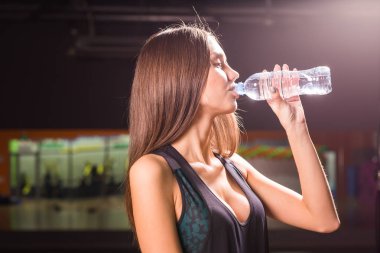Fitness kadın içme suyu şişe. Kas genç erkek spor salonunda egzersiz bir mola.
