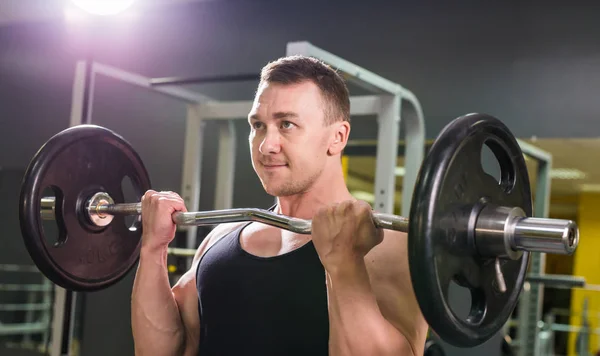 Muskulöser junger Mann stemmt Gewichte im Fitnessstudio — Stockfoto