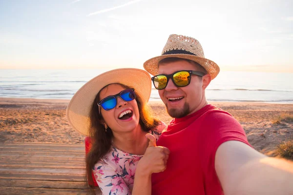 Glückliches reisendes verliebtes Paar, das an einem sonnigen Sommertag ein Handy-Selfie mit Koffern am Strand macht — Stockfoto