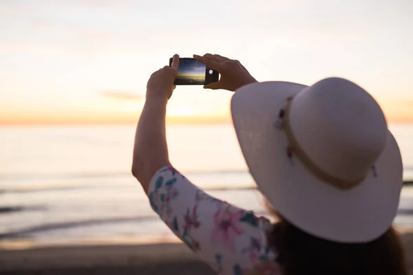 Fotoğraf gün batımı ve deniz cep telefonu veya smartphone dijital fotoğraf makinesi ile yazı için Online Internet iken seyahat tatil tatil çekici genç kadın. — Stok fotoğraf