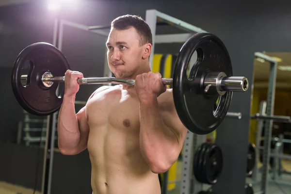 Schöner, kräftiger, athletischer Mann mit Langhantel. starker Bodybuilder mit Sixpack, perfektem Bauch, Schultern, Bizeps, Trizeps und Brust — Stockfoto