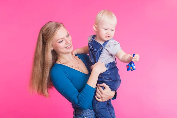 Feliz niña y su madre divirtiéndose sobre fondo rosa — Foto de Stock