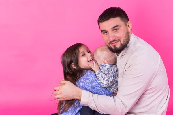 Schöner Vater mit seiner kleinen Tochter und seinem kleinen Sohn auf rosa Hintergrund — Stockfoto