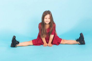 Güzel kız bir bölmeleri üzerinde oturuyor. mavi bir arka plan üzerinde izole