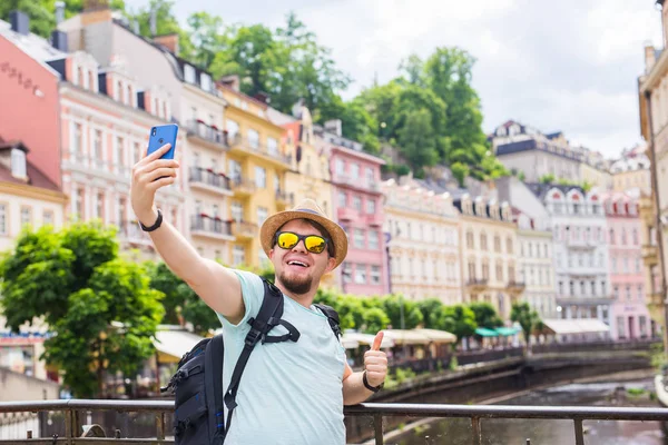 Hombre guapo tomando selfie con cámara de teléfono inteligente móvil en la ciudad europea. Concepto de vacaciones, viajes y vacaciones . — Foto de Stock