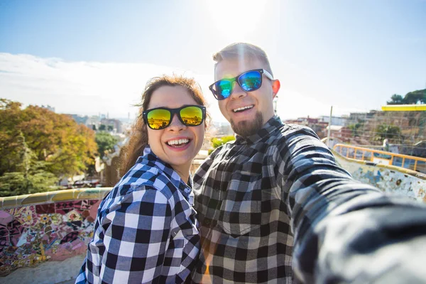 Travel couple happy making selfie portrait with smartphone in Park Guell, Barcelona, Spain. Beautiful young couple looking at camera taking photo with smart phone smiling in love — Stock Photo, Image