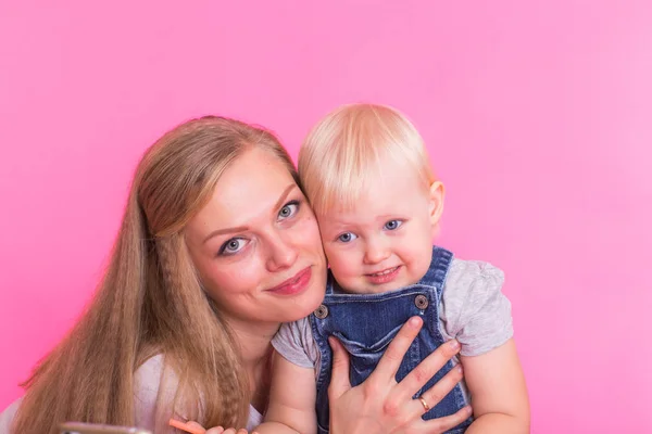 Mutlu küçük kız ve annesi pembe arka plan üzerinde eğleniyor — Stok fotoğraf